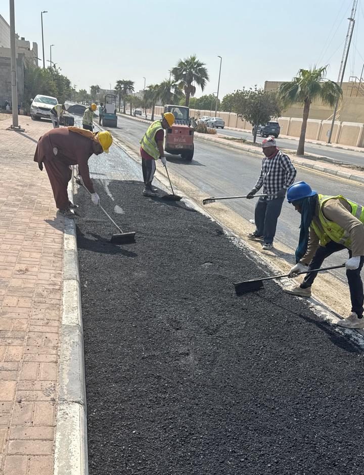 عمال يعيدون رصف الأسفلت فوق خندق ألياف